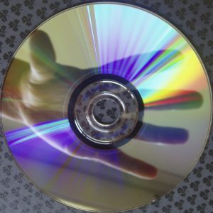 Image of a hand holding a CD with a rainbow reflection.