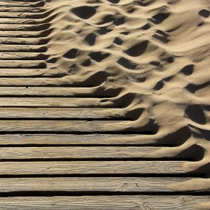 Image of sand blown across a beach boardwalk.
